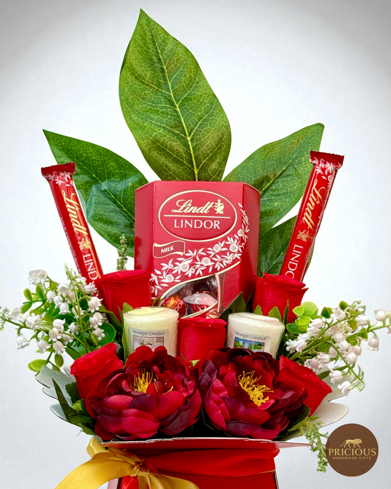 Close-up Lindt chocolate bouquet with red peonies and gold bow