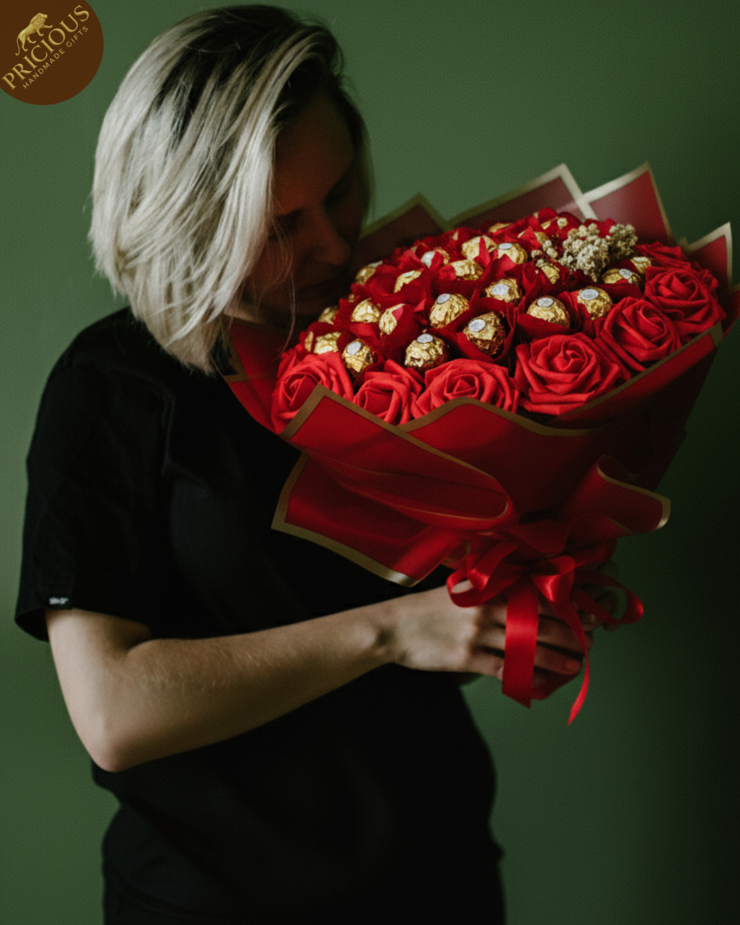 Person holding a bouquet of red roses and Ferrero Rocher chocolates against a dark background