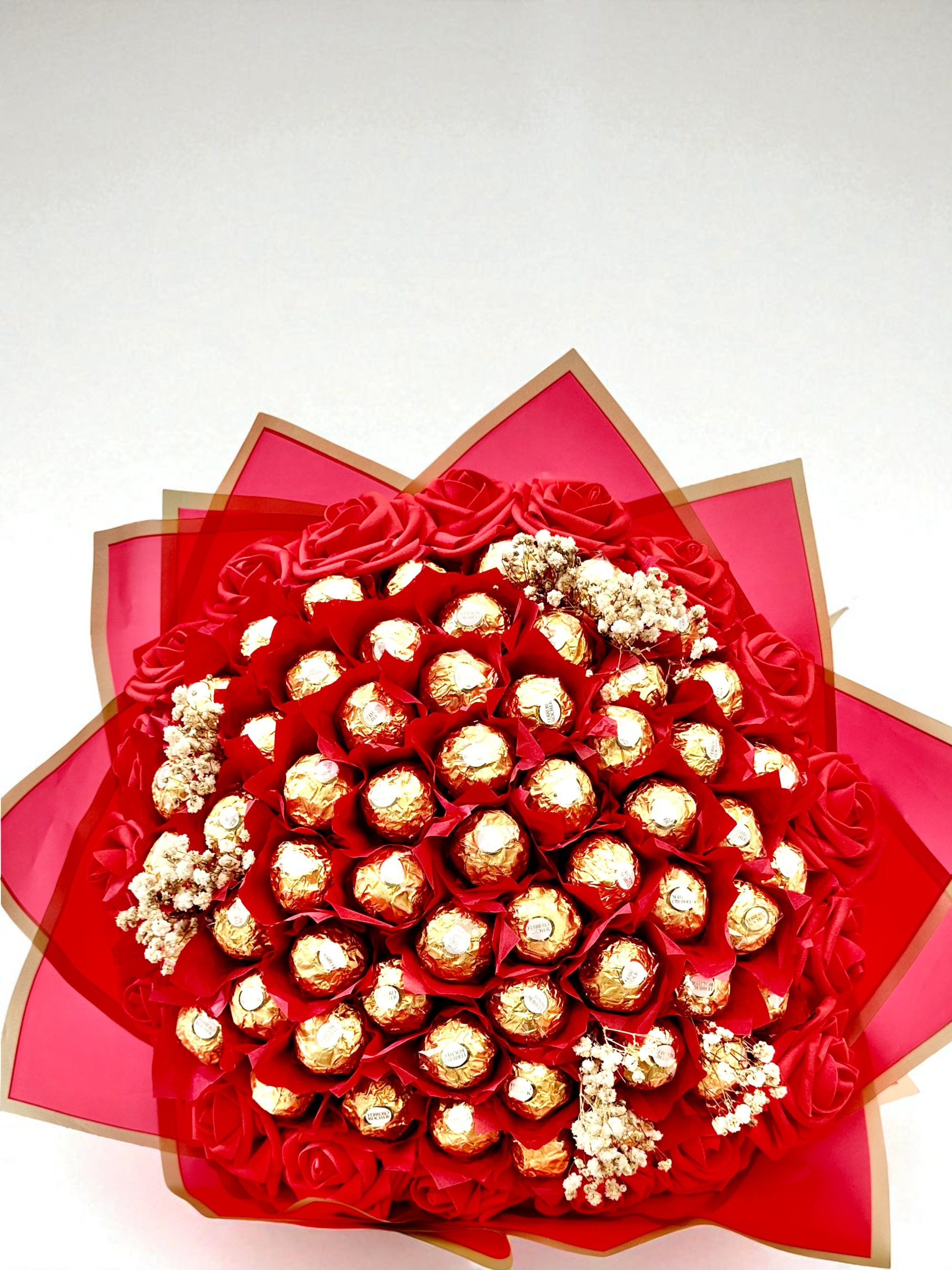 Bouquet of chocolates and flowers with orange and black ribbons on a beige background