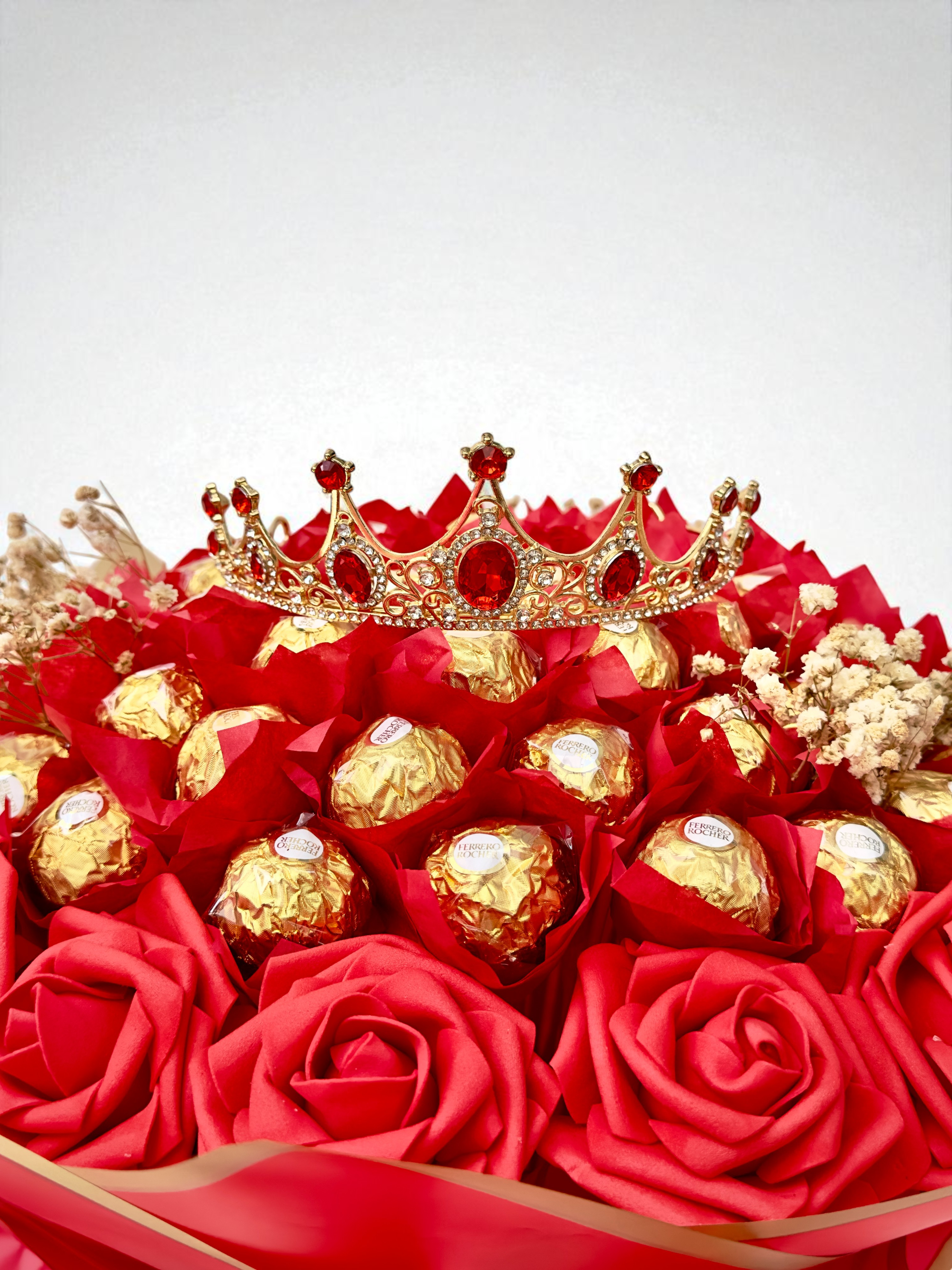 Bouquet of flowers and chocolates wrapped in burlap with ribbons on a beige background