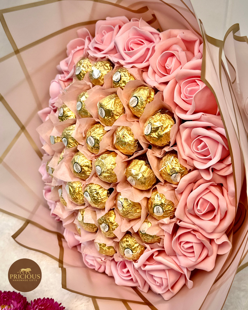 Bouquet of pink roses with gold Ferrero Rocher chocolates in a decorative box.