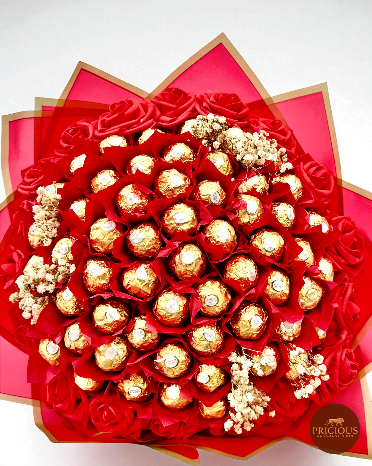 Bouquet of Ferrero Rocher chocolates wrapped in red paper with gold ribbons on a white background.