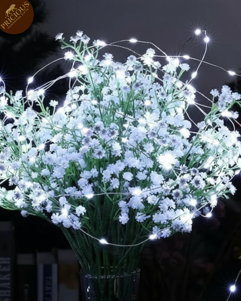 Bouquet of small white flowers with string lights against a dark background