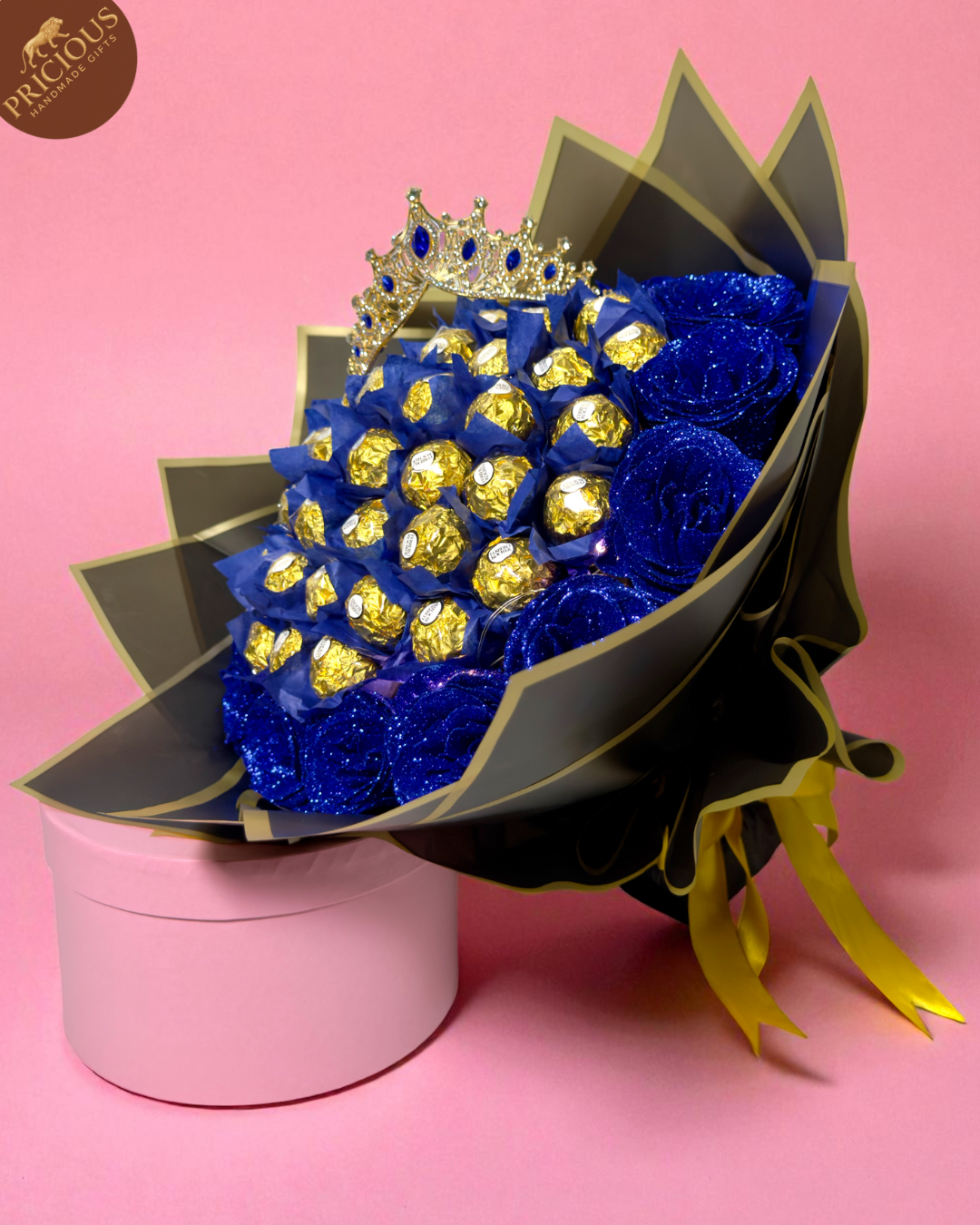 Hand-tied Ferrero Rocher bouquet with royal-blue artificial glitter roses and crown topper, black wrap with gold edge.