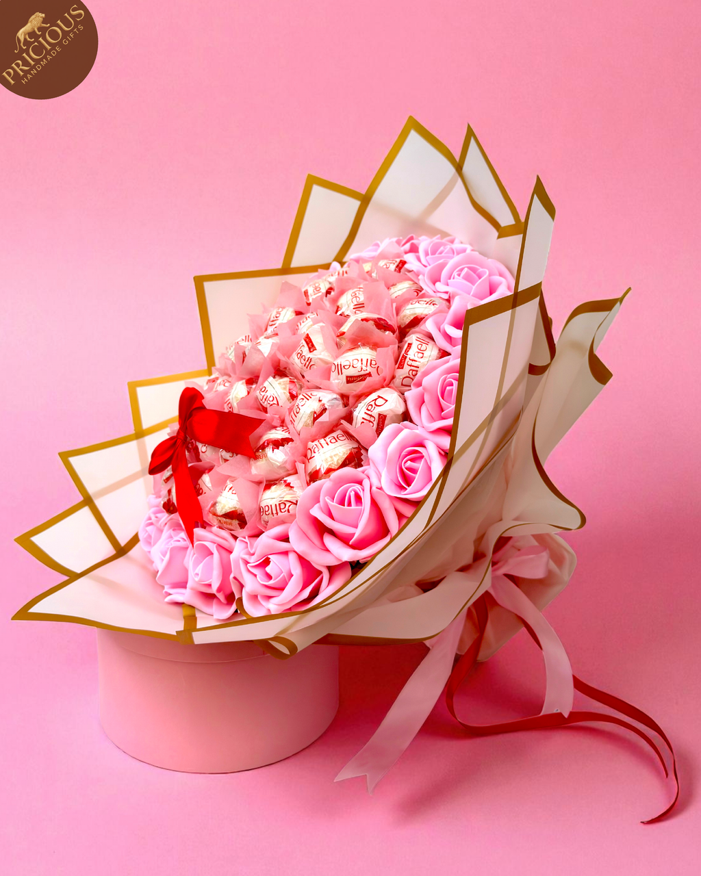 Hand-tied Ferrero Raffaello chocolate bouquet with pink artificial foam roses, white & gold wrap.
