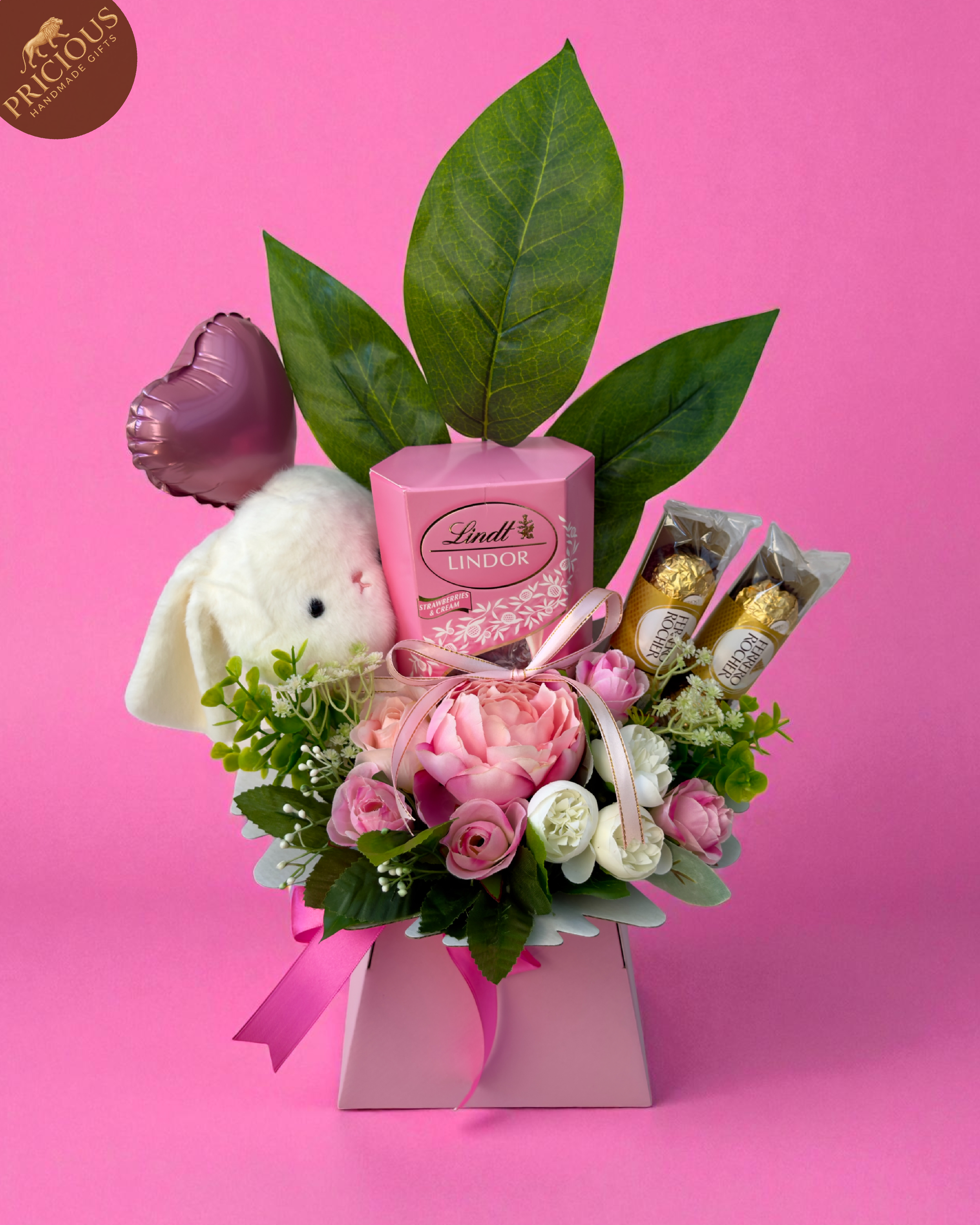 Pink baby girl bouquet box with Ferrero Rocher, Lindt Lindor and artificial roses, hand-arranged with plush bunny.