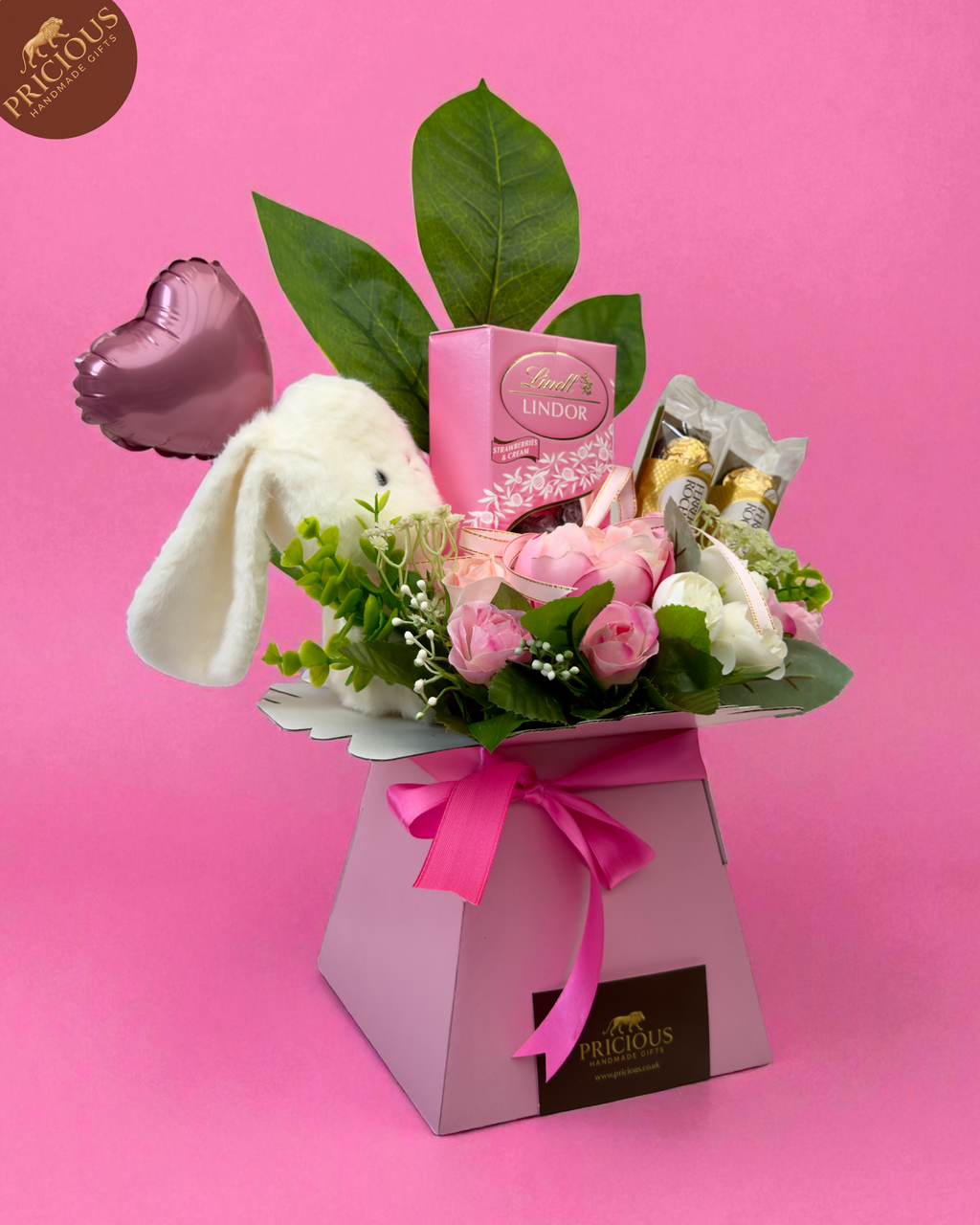 Side-view pink baby girl bouquet box with Ferrero Rocher, Lindt Lindor and artificial roses, hand-arranged with plush bunny.
