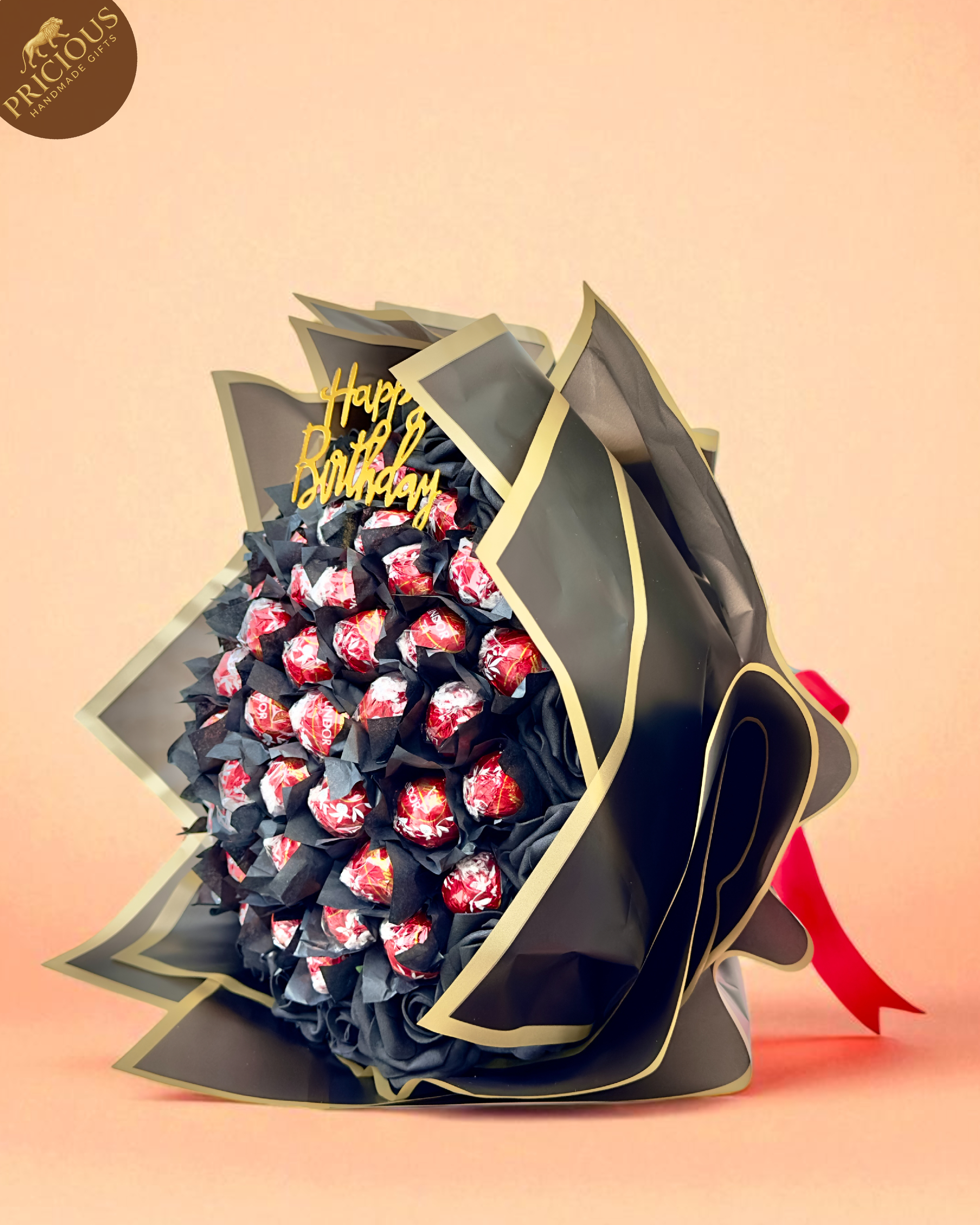 Hand-tied Lindt Lindor birthday chocolate bouquet in black & gold with artificial roses.