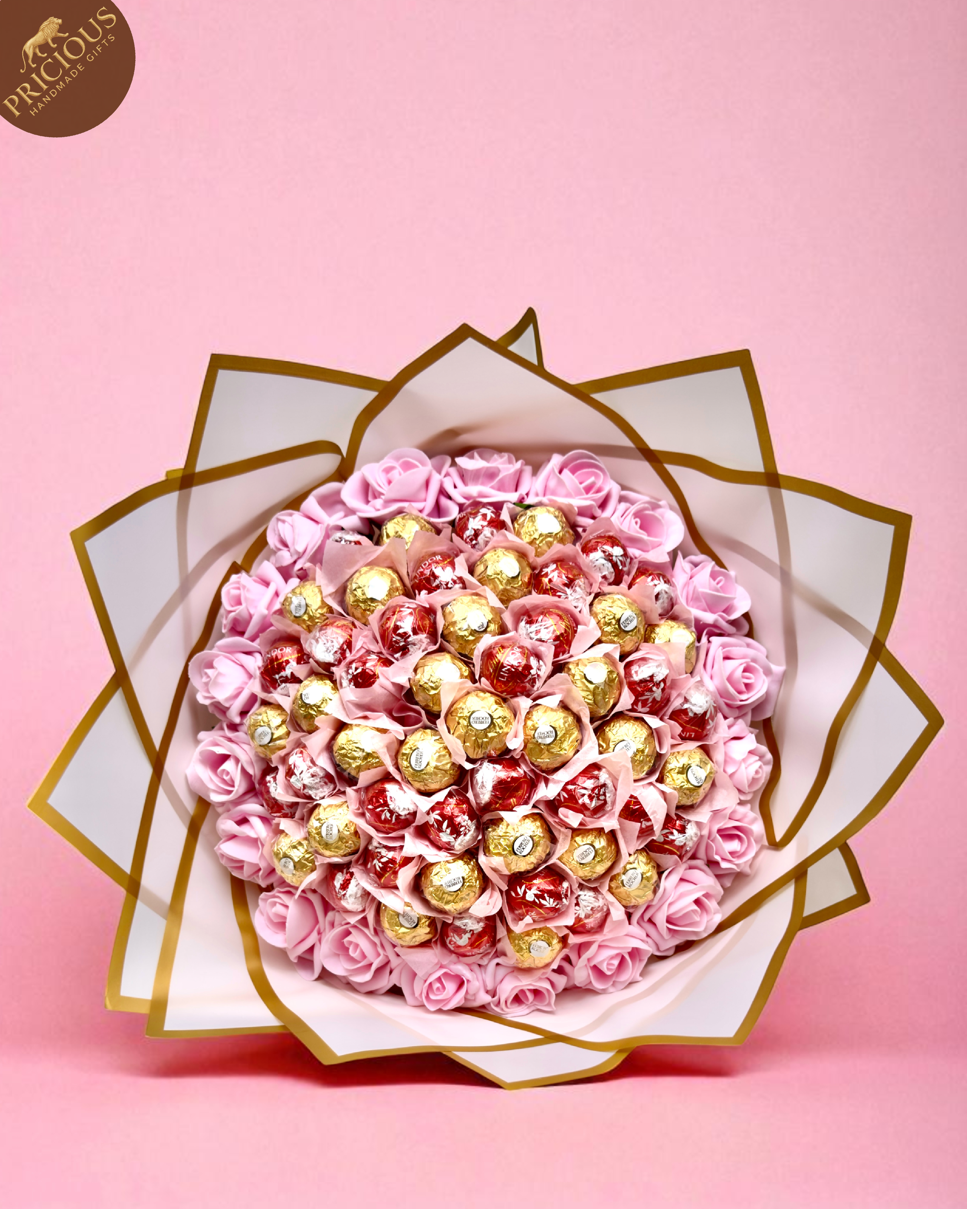 Mixed Ferrero & Lindor truffle bouquet, pink artificial roses with gold-edged wrap and satin bow.