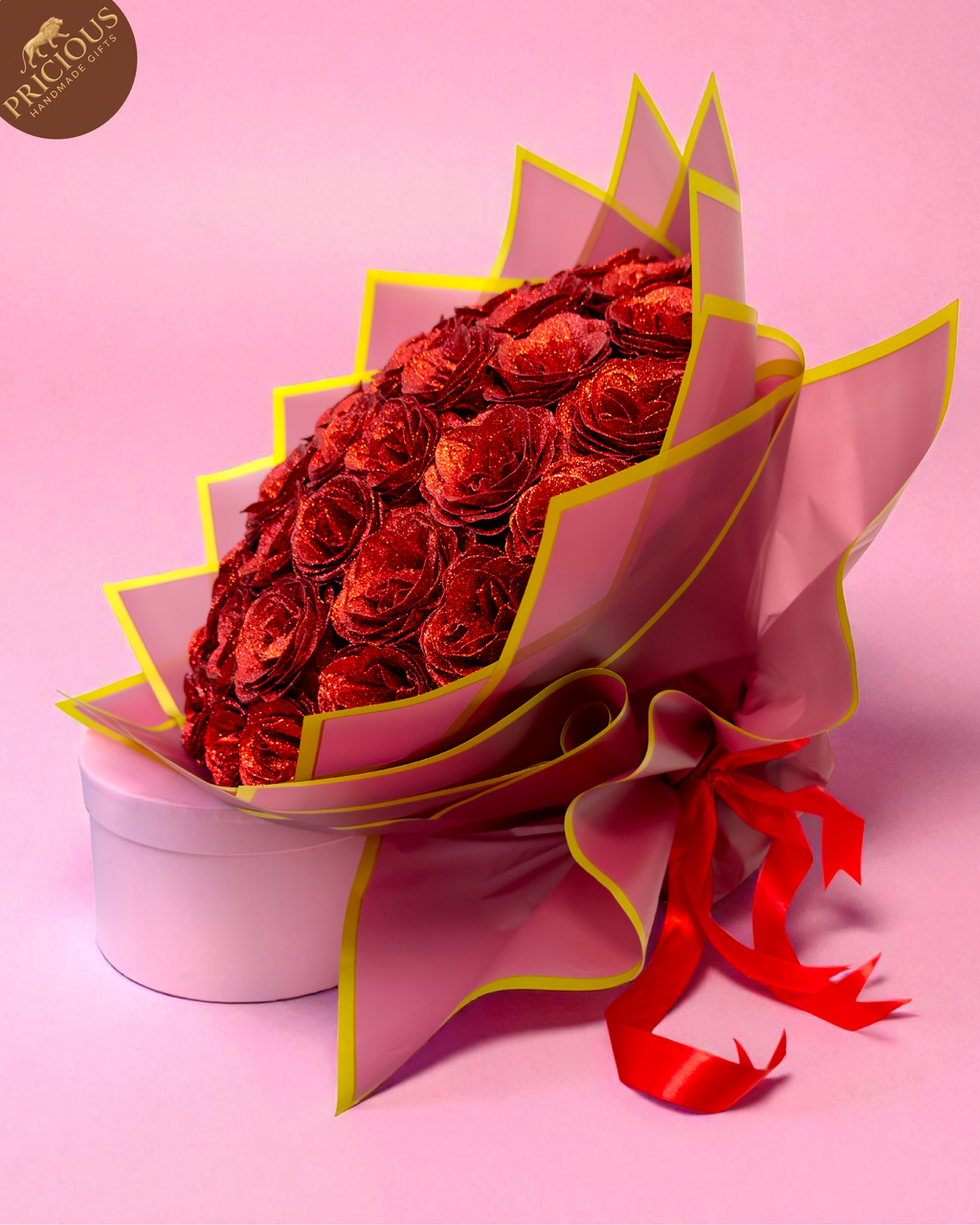 Hand-tied bouquet of glitter red artificial roses in blush-pink wrap with gold edge.