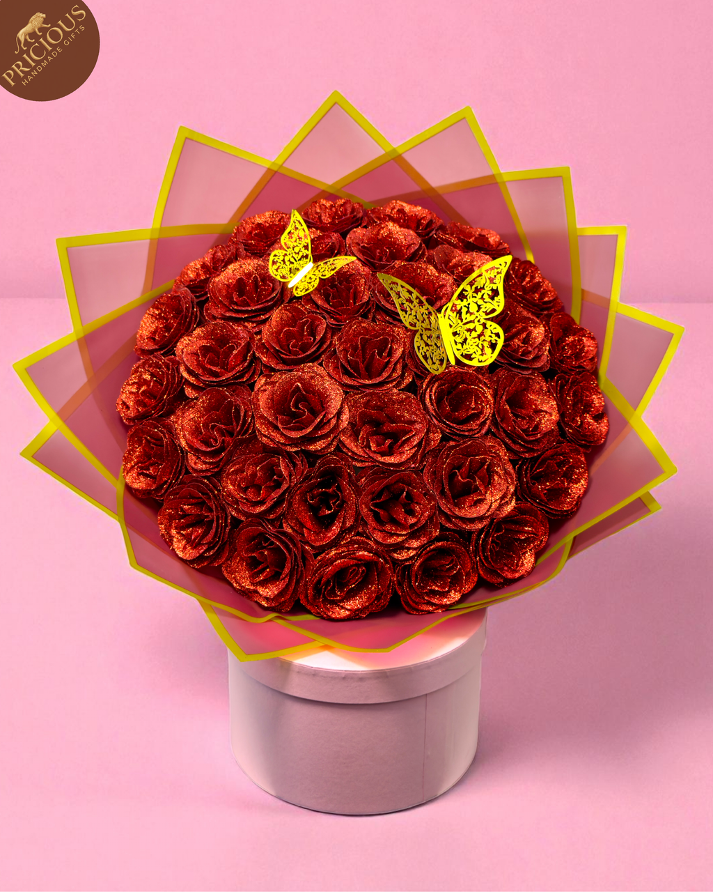 Top view of red glitter artificial roses hand-tied bouquet, butterfly accents, pink hat box display.